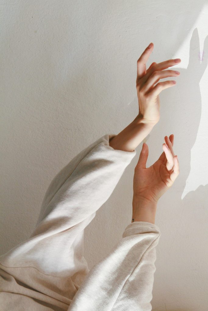Artistic capture of hands creating shadows on a wall, with soft light and minimalist aesthetic.
